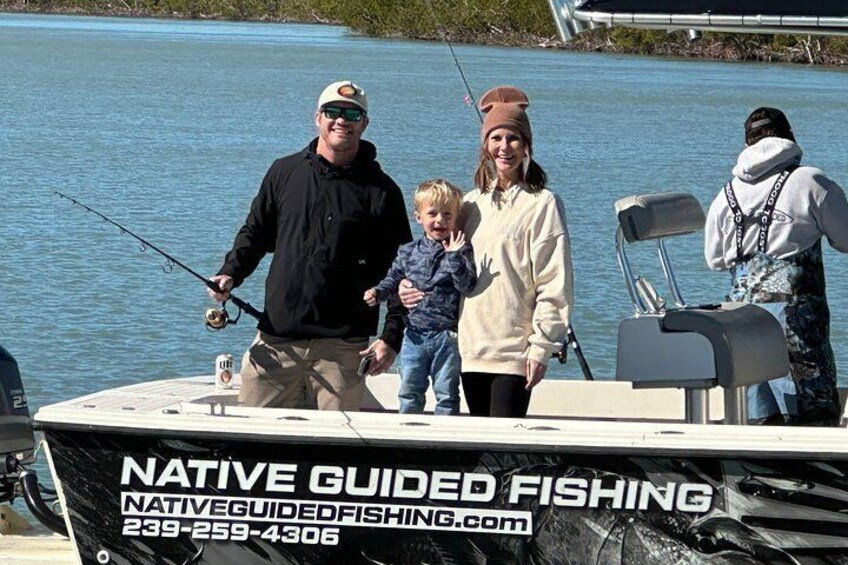 A boat with people fishing, a calm lake, and a dock in the background. 2