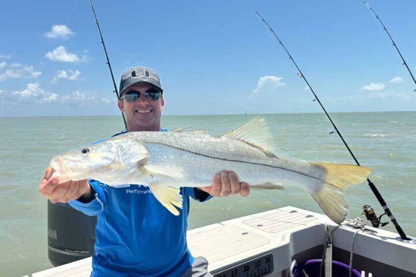 A person holding a fish on a boat with fishing rods. 5
