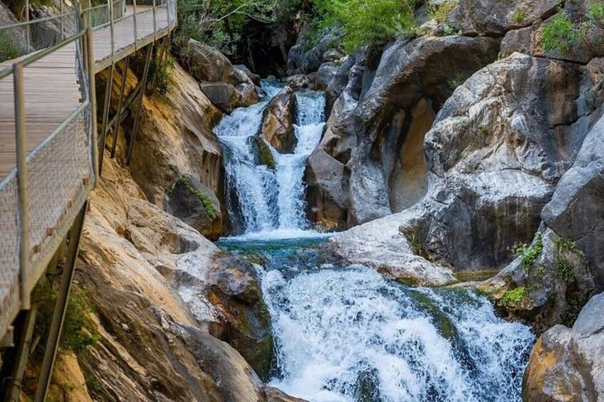 A multi-tiered waterfall with a wooden walkway on the left. 1