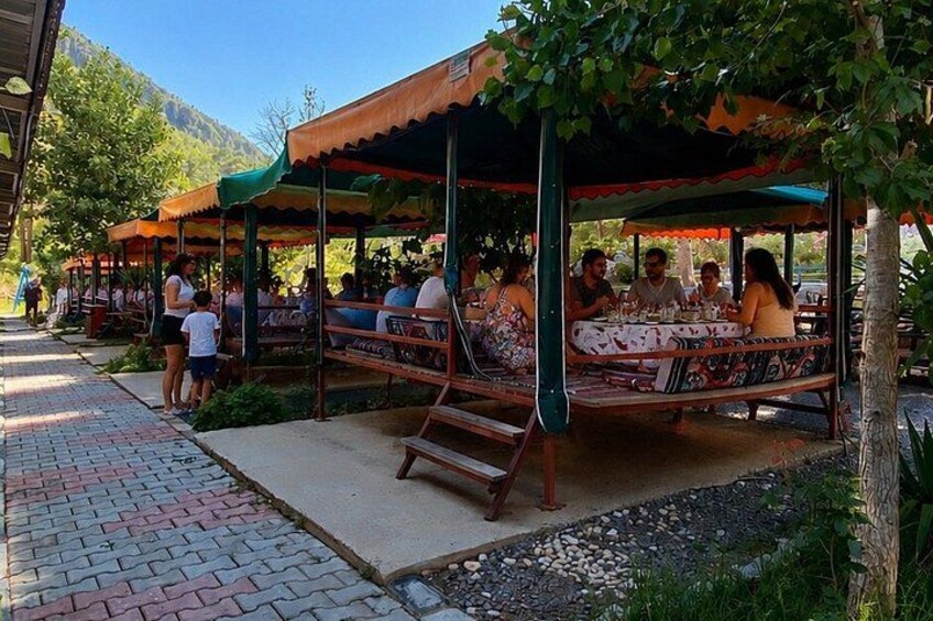 Outdoor seating areas with people dining under canopies, surrounded by greenery and a mountainous backdrop. 3