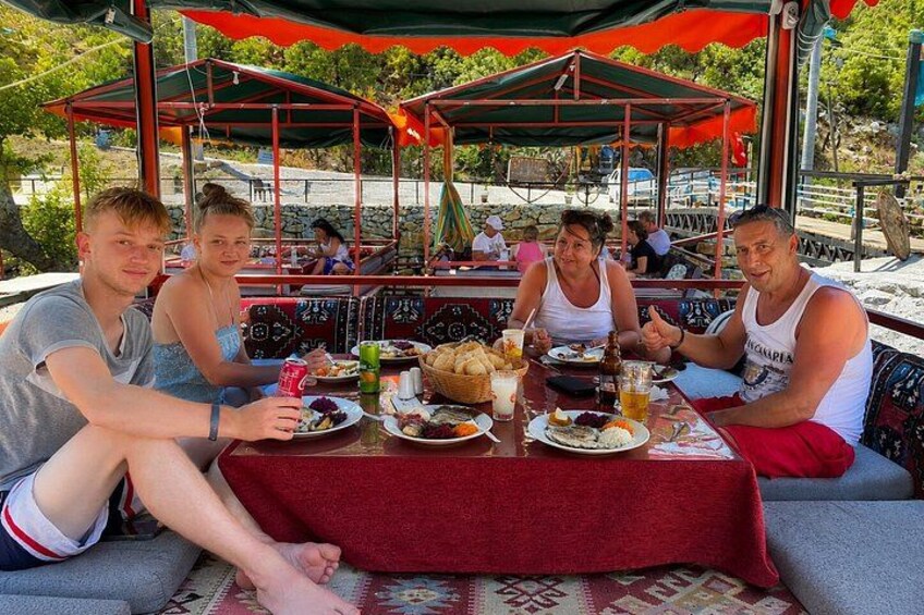 A group of people dining at an outdoor restaurant with a red tablecloth. 4