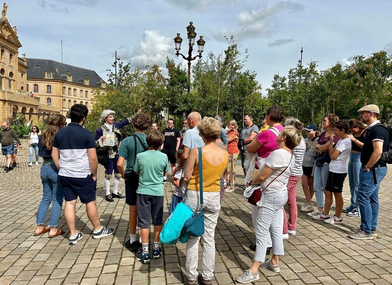 A group of people gathered in a public square with historic buildings and a lamppost in the background. 2
