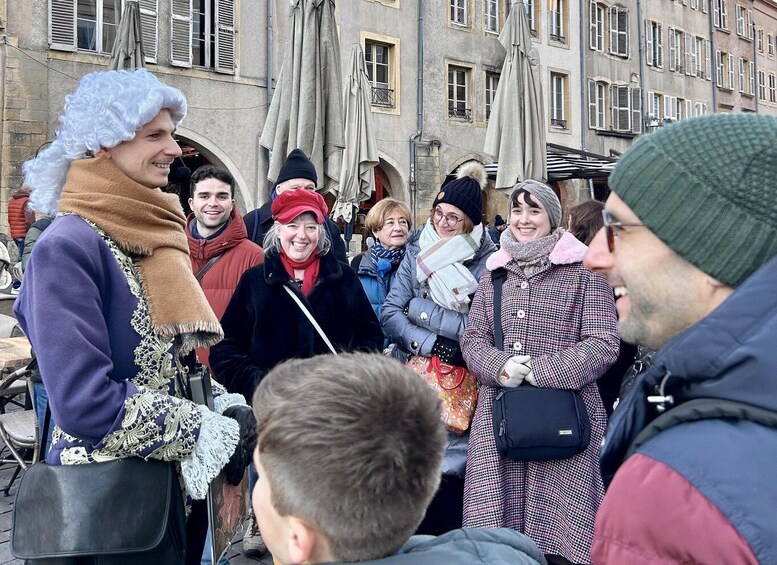 A group of people in winter clothing standing outdoors in front of a building with multiple windows and awnings. 4