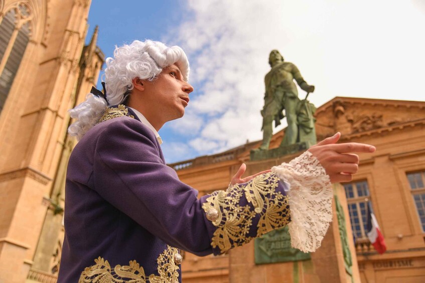 A person in historical costume with a statue in the background. 1