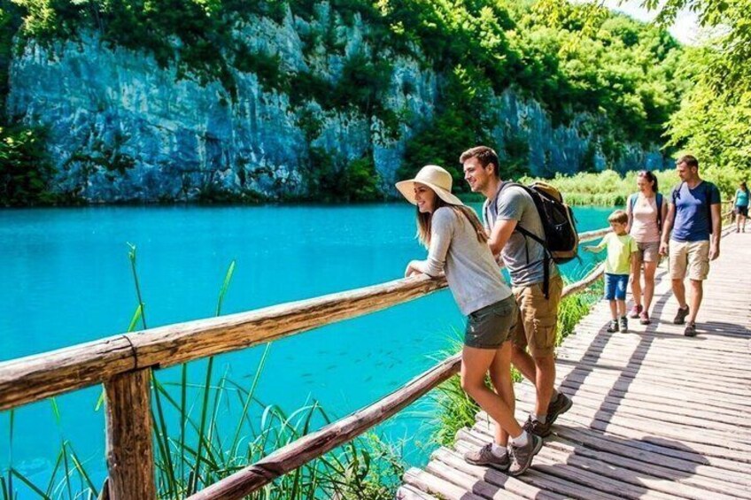 A wooden boardwalk by a turquoise lake with rocky cliffs. 1