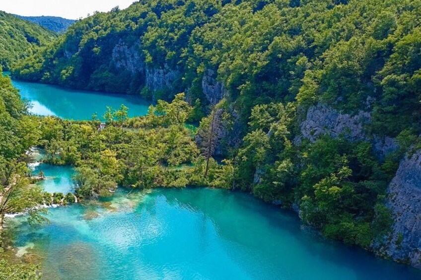 A turquoise river winding through a forested valley with steep cliffs. 3