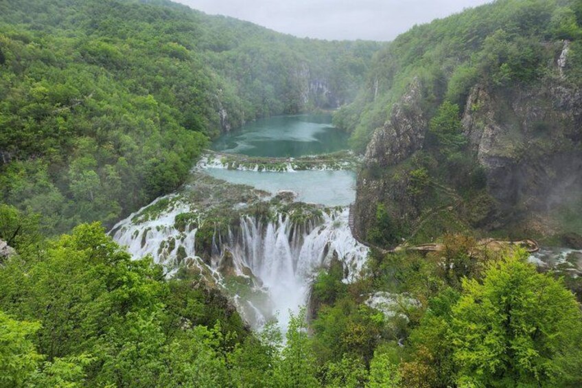 A waterfall cascading into a lake surrounded by dense forest. 2