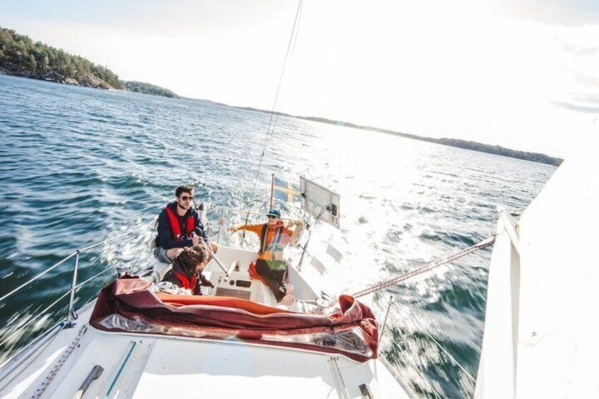 A sailboat on water with a person steering and another person standing. 4