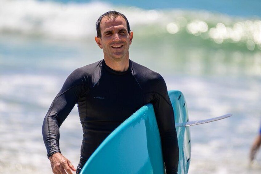 A person in a wetsuit carrying a blue surfboard. 1