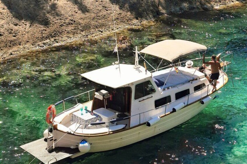 A boat docked at a rocky shore with clear water. 5