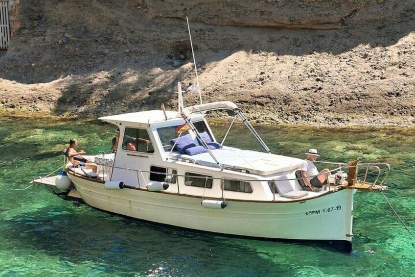 A boat with two people on board, anchored near a rocky shore. 1