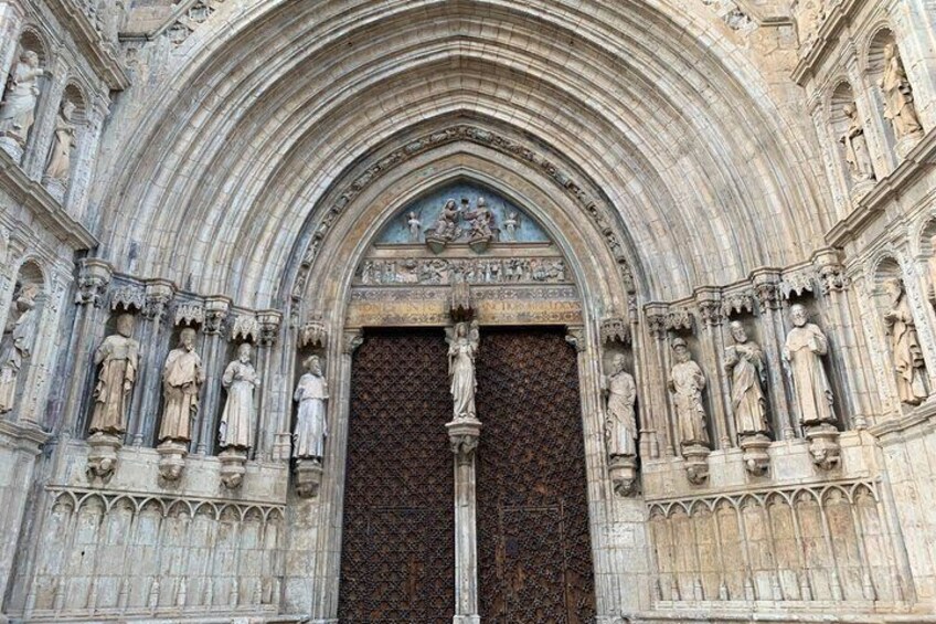 A Gothic cathedral entrance with intricate stone carvings and a large wooden door. 2