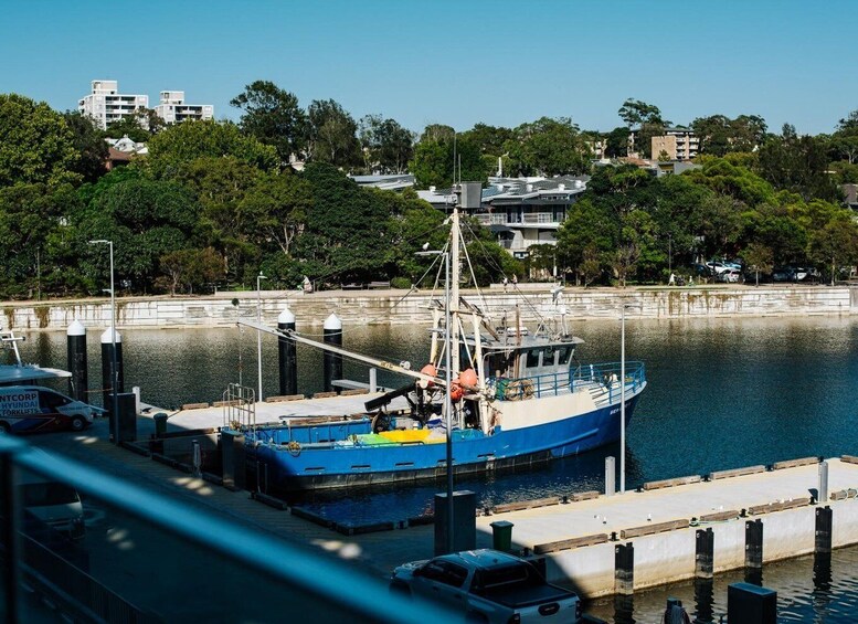 A blue fishing boat docked at a pier with a cityscape in the background. 2