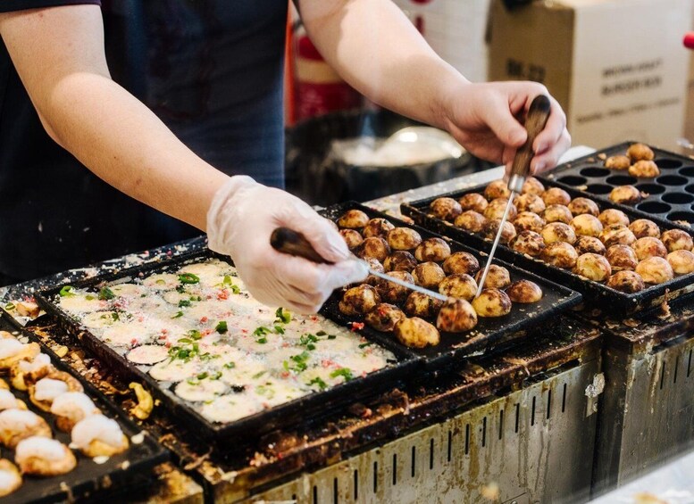 A person grilling food on a griddle with tongs. 1