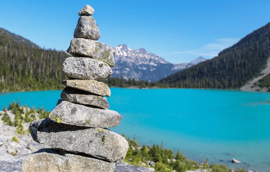 A stack of rocks in a mountainous landscape with a turquoise lake. 3