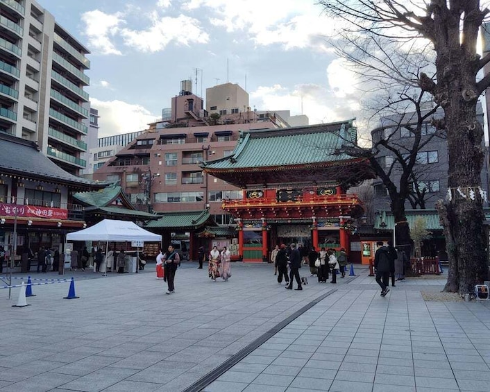 A traditional Japanese temple with a red torii gate, surrounded by modern buildings and a clear sky. 5