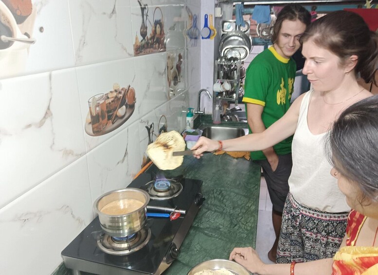 A person cooking on a stove in a kitchen with white marble tiles and various kitchen utensils. 4