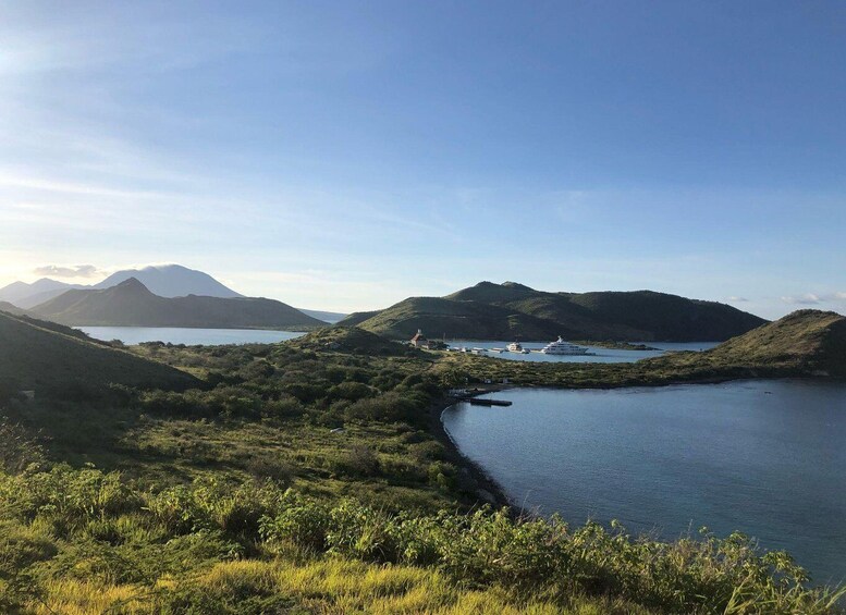 A coastal landscape with hills, a body of water, and boats. 1