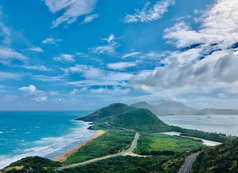 A coastal landscape with a winding road, a beach, and a mountain in the distance. 2