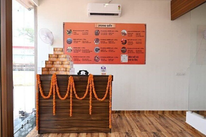 A reception desk with a wooden counter, a wall-mounted fan, and a poster with text and images. 3