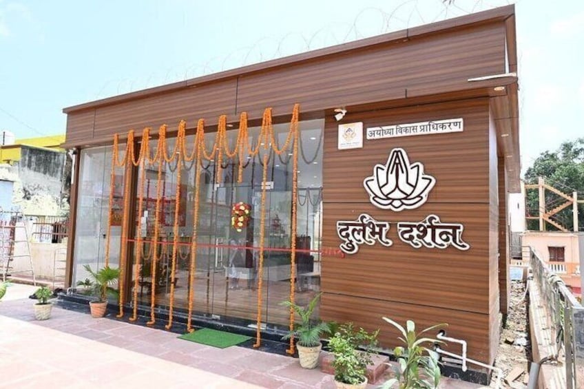 A wooden building with a glass door, adorned with orange garlands and a prayer symbol. 1
