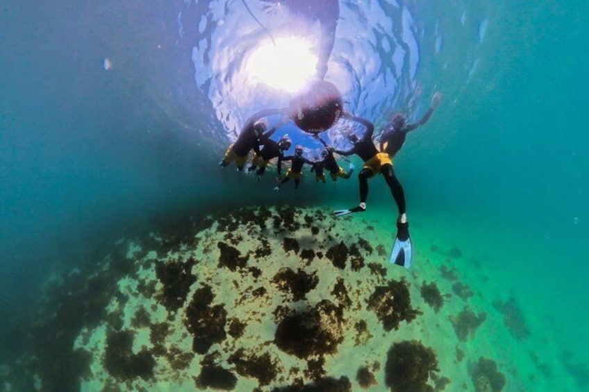 Divers exploring an underwater cave with visible rock formations and a light source. 2