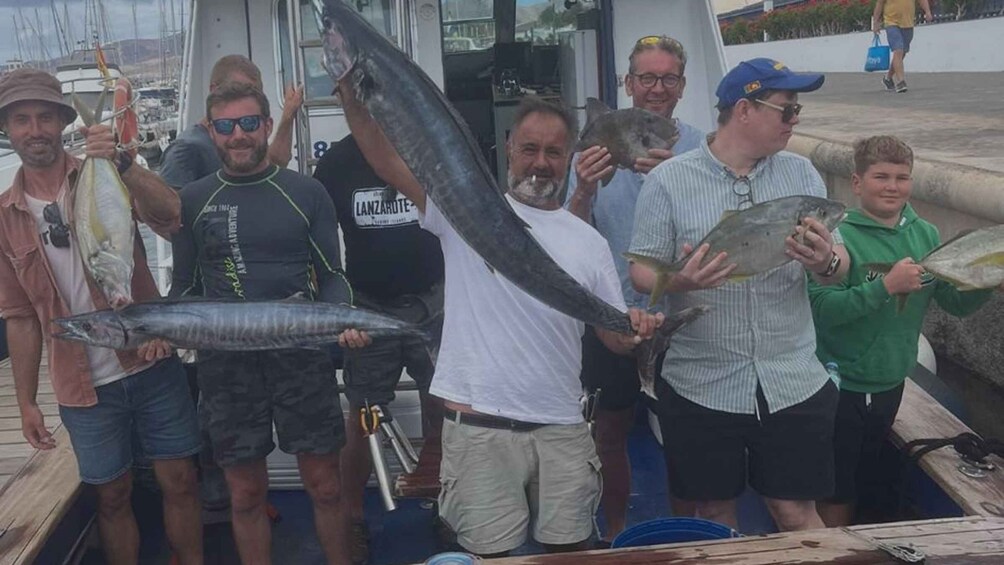 A group of people on a boat holding large fish. 5