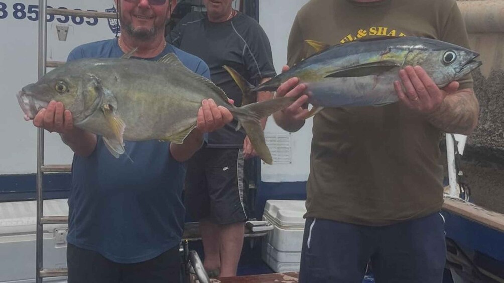 Two people holding fish on a boat. 1