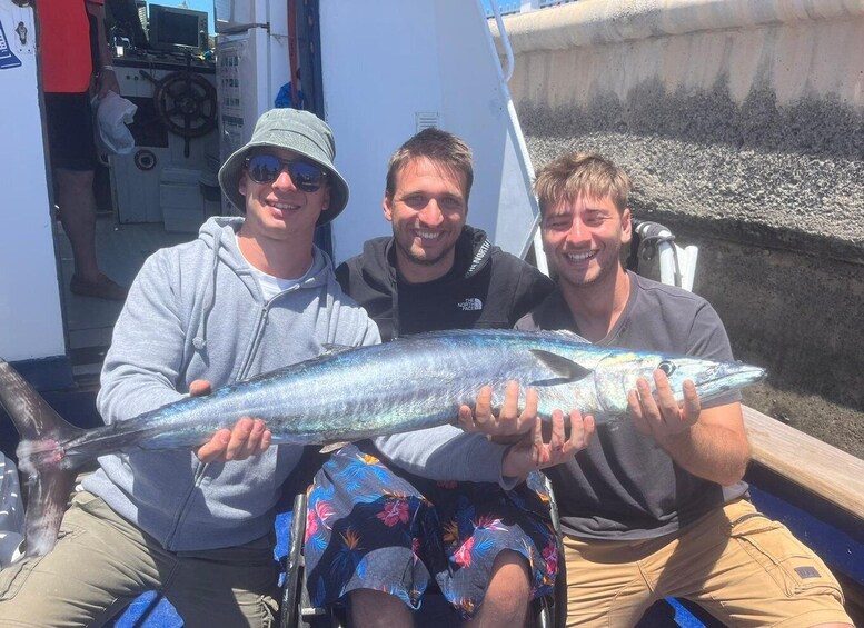Three people holding a large fish on a boat. 4