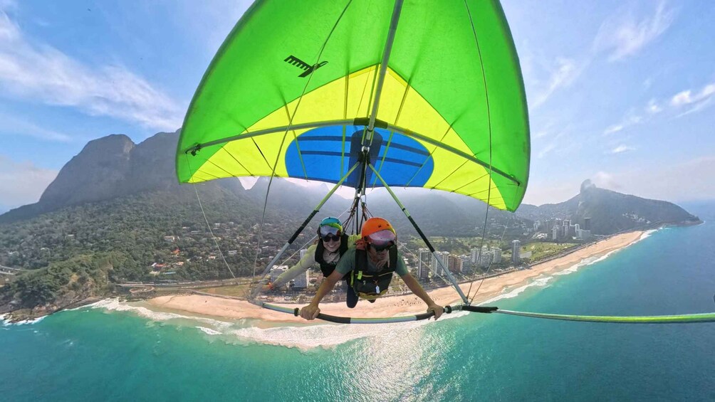 A paraglider flying over a coastal area with a mountain in the background. 1