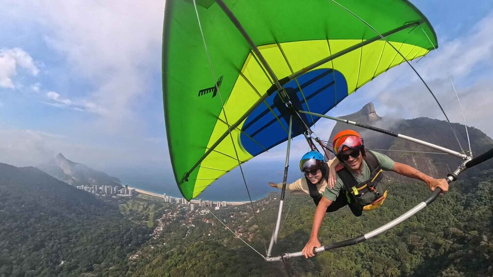 A person paragliding with a green and blue parachute over a mountainous landscape. 5