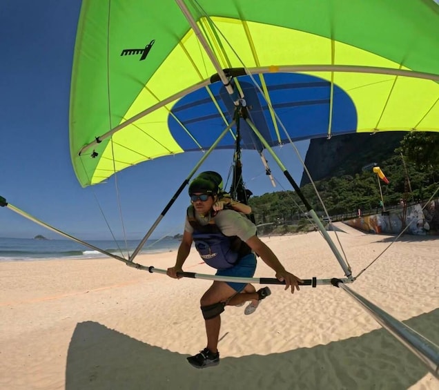 A person windsurfing on a beach with a green and yellow sail. 5
