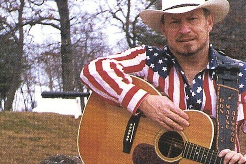 A person playing an acoustic guitar outdoors. 1