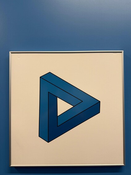 A framed geometric artwork on a blue wall. 3