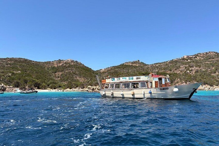 A boat on a clear blue sea with a mountainous backdrop. 2