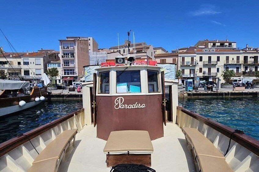 A boat named 'Paradiso' docked at a marina with buildings in the background. 3