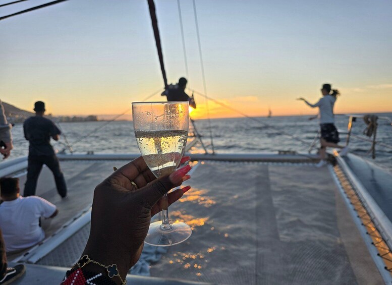 A person holding a glass of water on a boat with a sunset in the background. 4