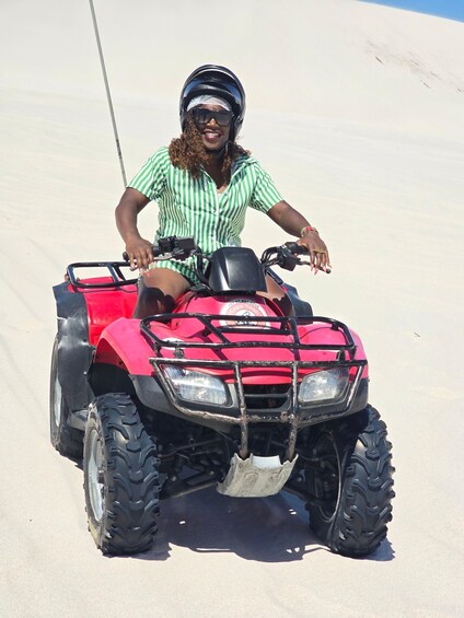 A person riding a red ATV on a sandy terrain. 3