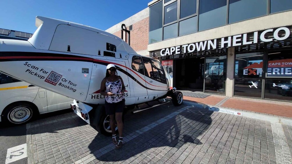 A white helicopter parked in front of Cape Town Helico, with a QR code for booking or tour pickup. 5