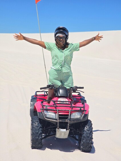 A person on a red ATV in a desert with a flag. 2