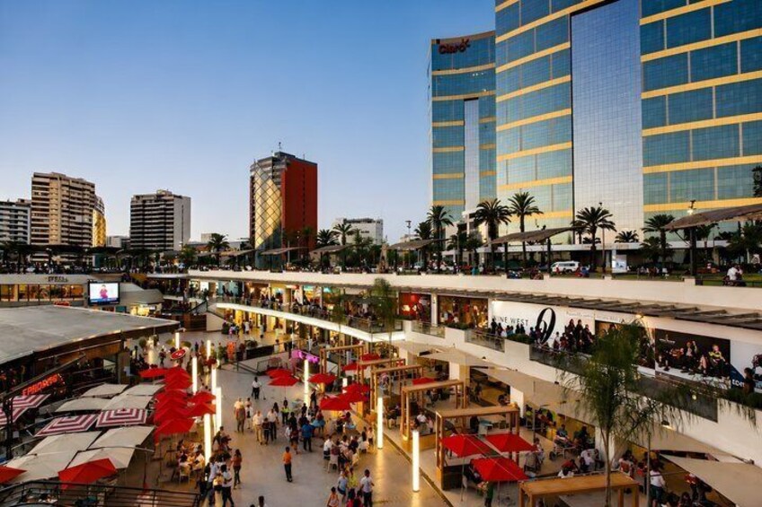 A bustling urban plaza with multiple levels of shops and restaurants, surrounded by high-rise buildings. 4