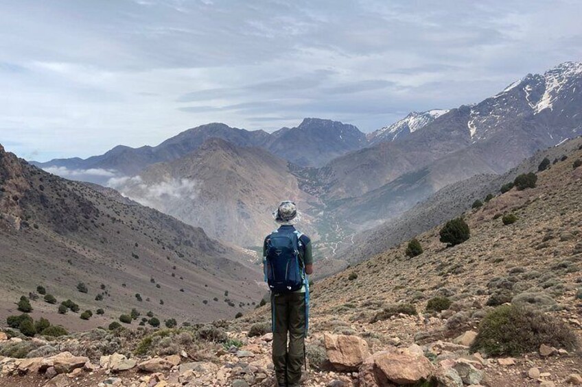 A person hiking in a mountainous area with rocky terrain and sparse vegetation. 4
