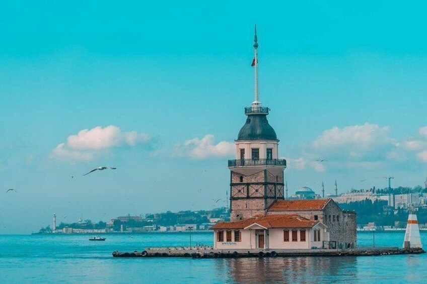 A coastal tower with a flag, a lighthouse, and a building with a red roof. 1
