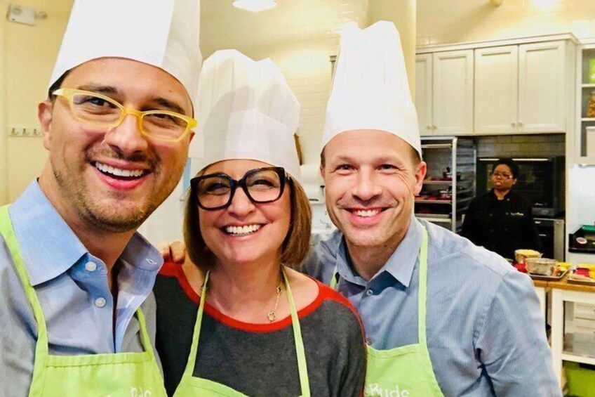 Three people wearing chef hats and aprons in a kitchen. 4