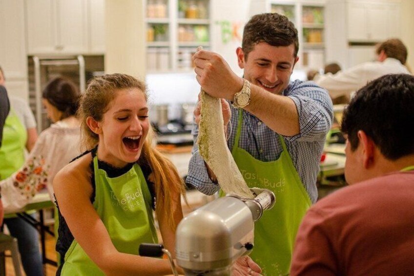 People in a kitchen, one person is kneading dough. 5