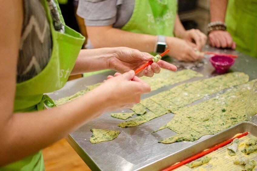 People preparing food, specifically cutting dough on a metal surface. 2