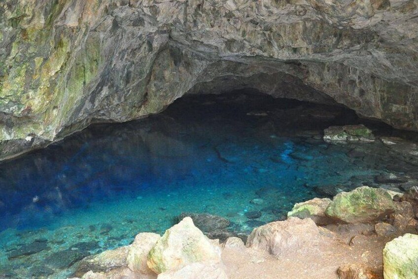 A cave entrance with clear blue water and rocky formations. 5