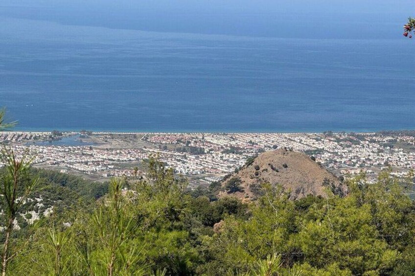A coastal cityscape with a prominent hill in the foreground and a view of the ocean. 3