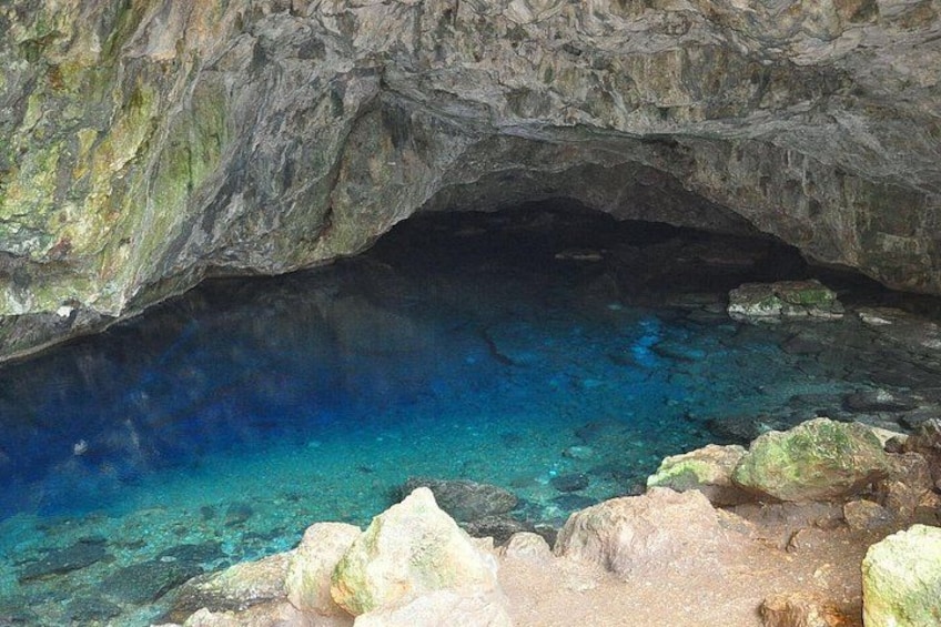 A cave entrance with clear blue water and rocky formations. 4