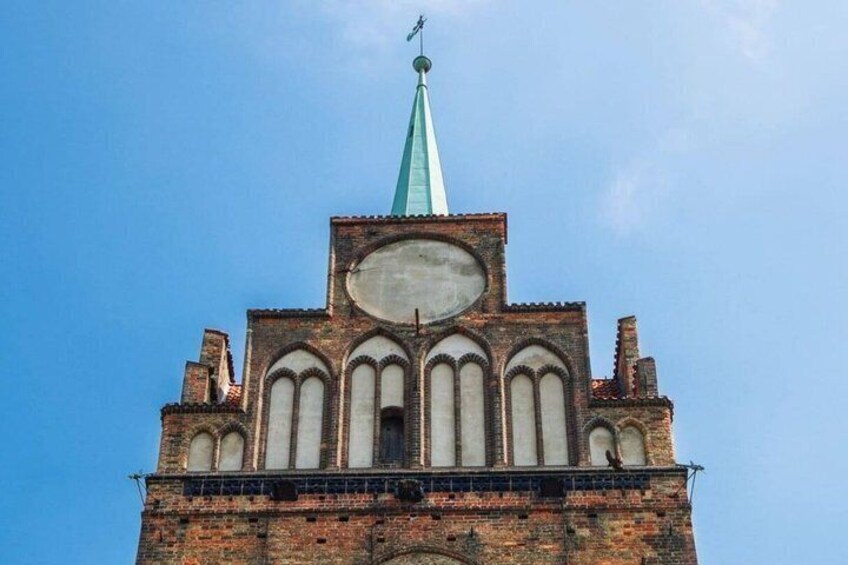 A church with a tall spire and a large clock. 5